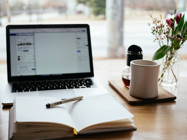 Professional small business website design service in Eastern North Carolina. Picture of a laptop with an open book and pen and a cup of coffee.