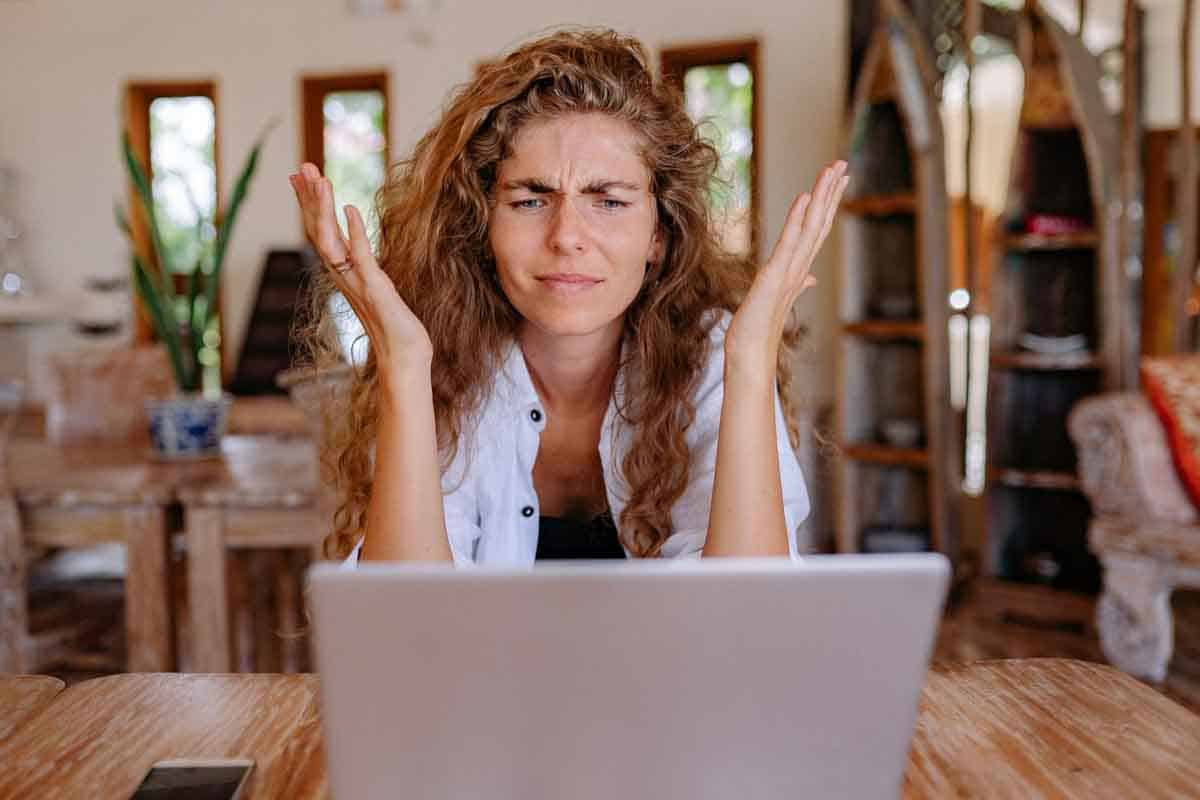 Woman in front of a laptop screen looking like she's trying to make a decision, as discussed in the blog post "Should I build my own website or pay someone?"